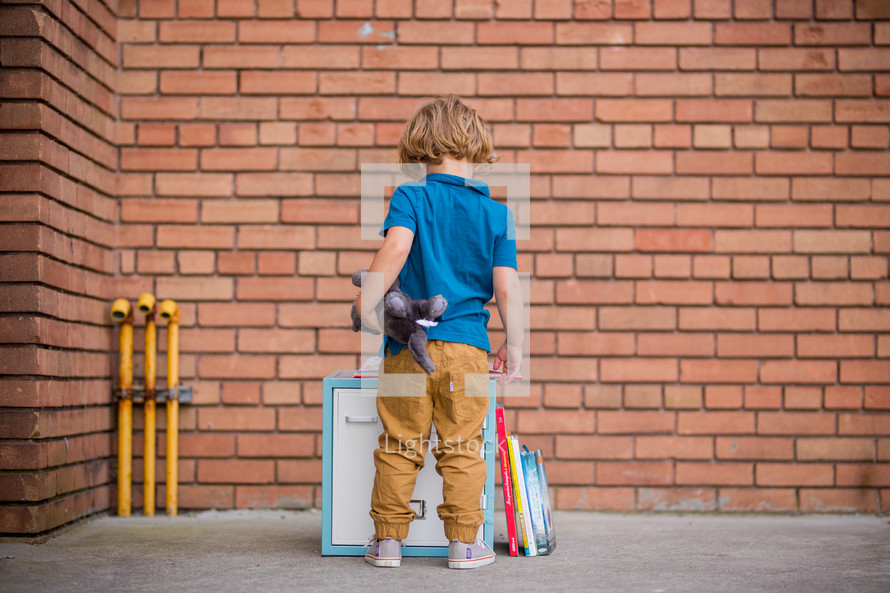 a child standing in front of locker reading a book 