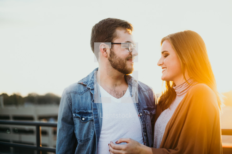 a couple standing on a bridge at sunset 
