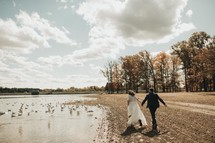bride and groom running on a beach 