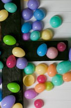 Colorful plastic Easter eggs on a wooden cross.