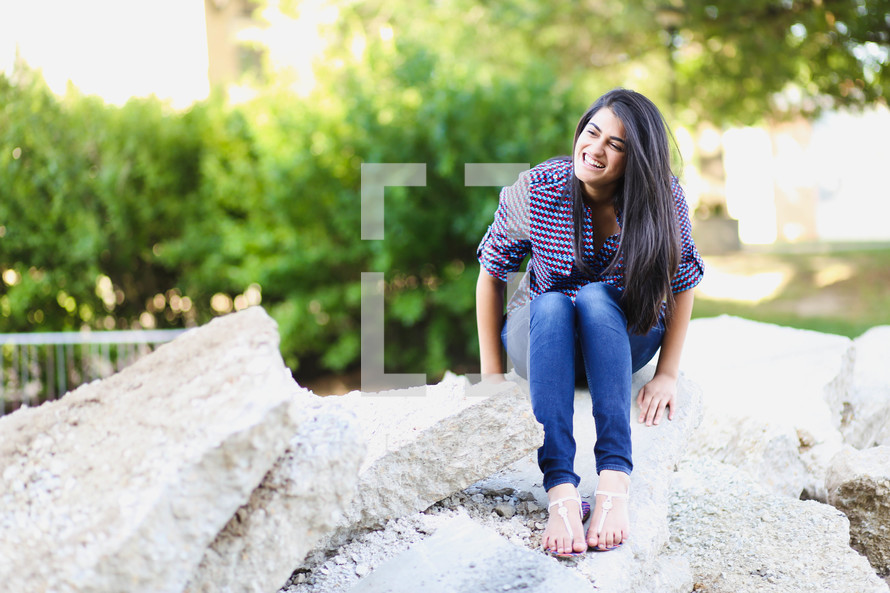 young woman sitting on rocks outdoors 