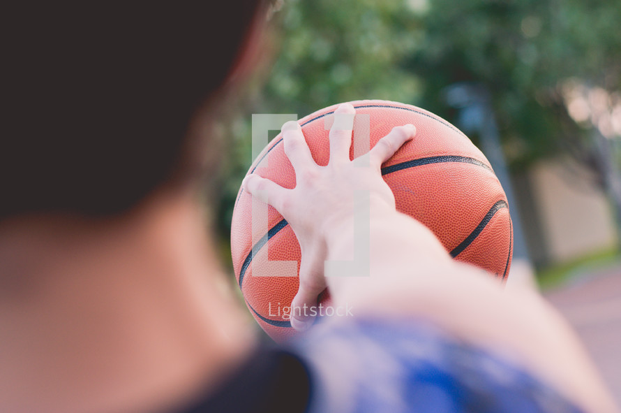 teen boy gripping a basketball 