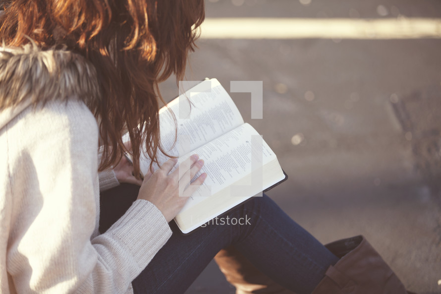 Woman sitting outside reading the Bible.