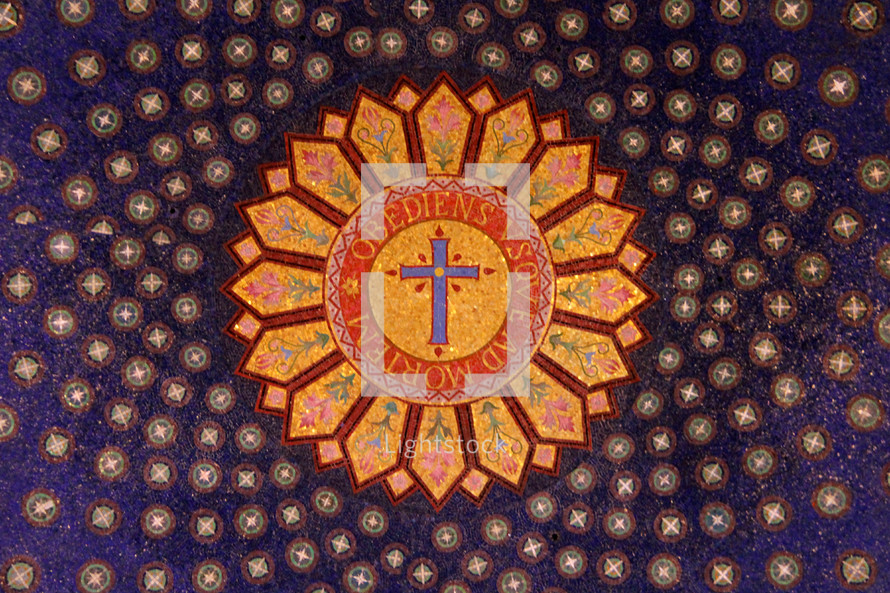 Ornate mosaic on the ceiling of the basilica with a cross and Latin words "obediens sovead morten' meaning "obedient until death."