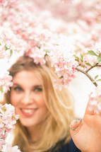 Smiling woman behind pink flowers.