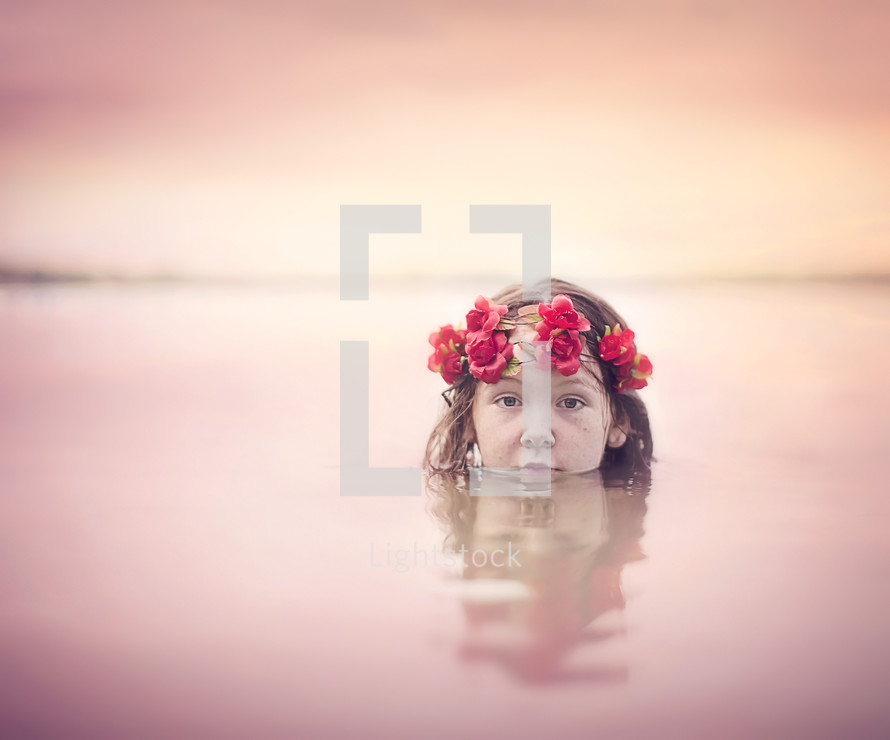 child with a crown of flowers in water 