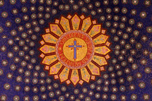 Ornate mosaic on the ceiling of the basilica with a cross and Latin words "obediens sovead morten' meaning "obedient until death."