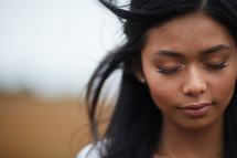 face of a young woman with closed eyes praying 