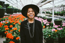 An African American woman in a black hat standing in a greenhouse 
