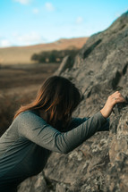 Rock climbing lady, woman mountain climbing wearing a long sleeve sports shirt, gripping rocks, bouldering outdoor sports and activities