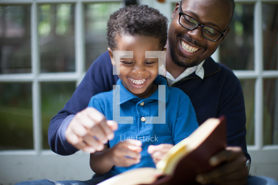 Father and son happily reading the Bible together.