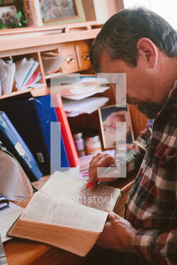 a man sitting at a desk reading a Bible 
