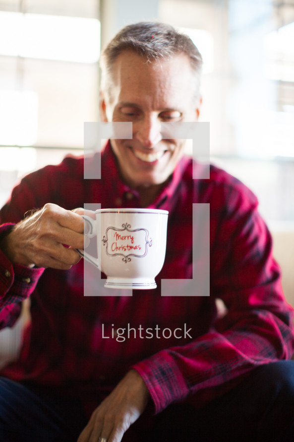 A smiling man holding a cop of coffee