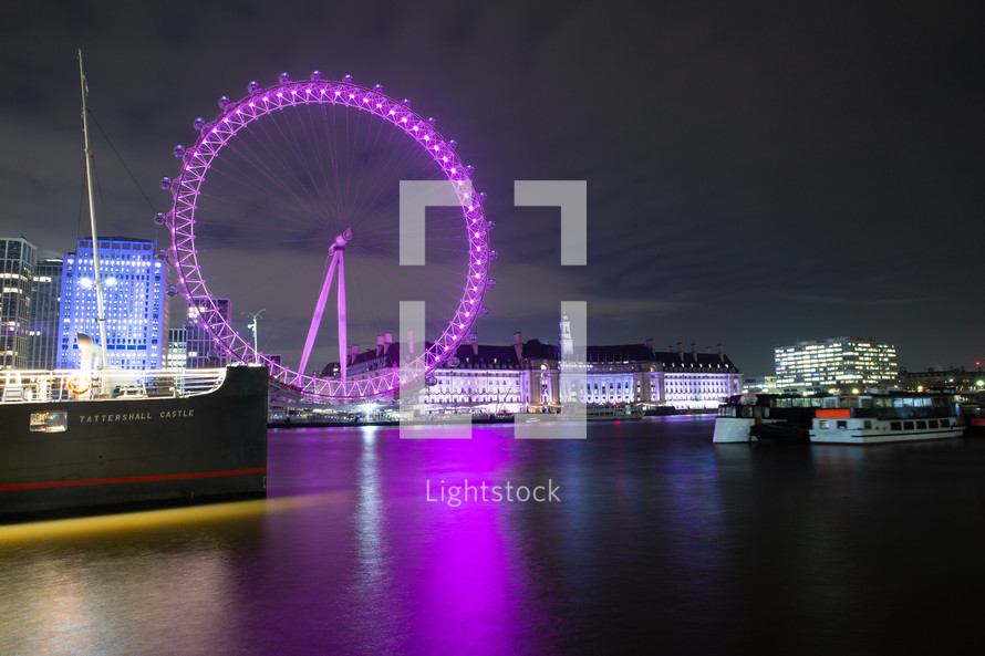 purple ferris wheel by a waterway at night 