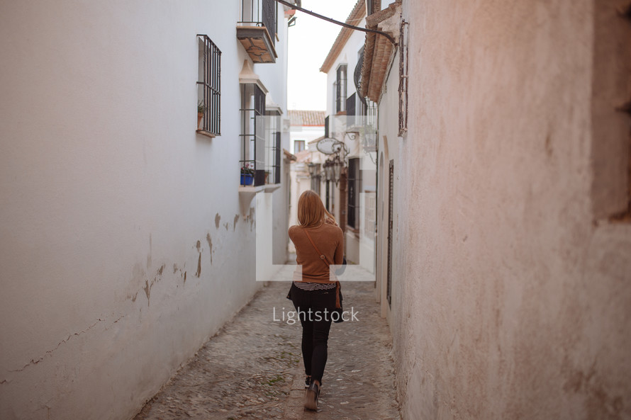 a woman walking through a narrow alley 
