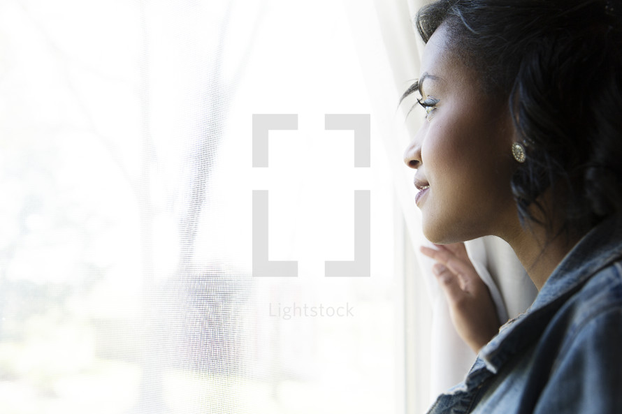 An African American woman looking out a window 