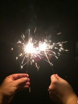 hands holding up sparklers 