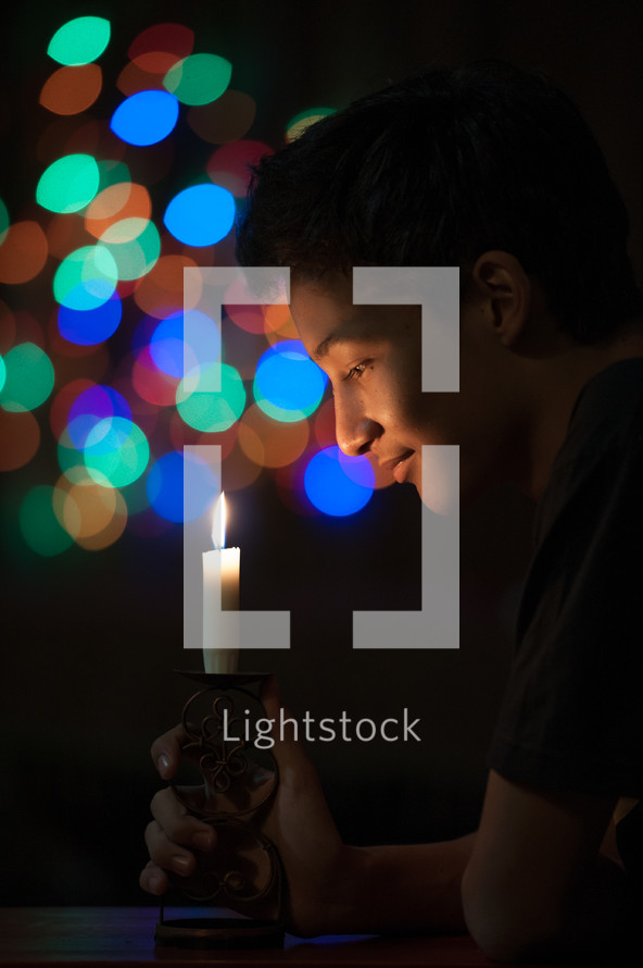 colorful bokeh lights and a boy holding a candle