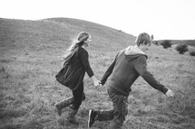 a couple holding hands running in a field