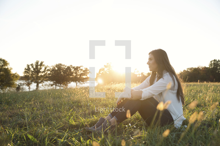 woman sitting in grass outdoors thinking 