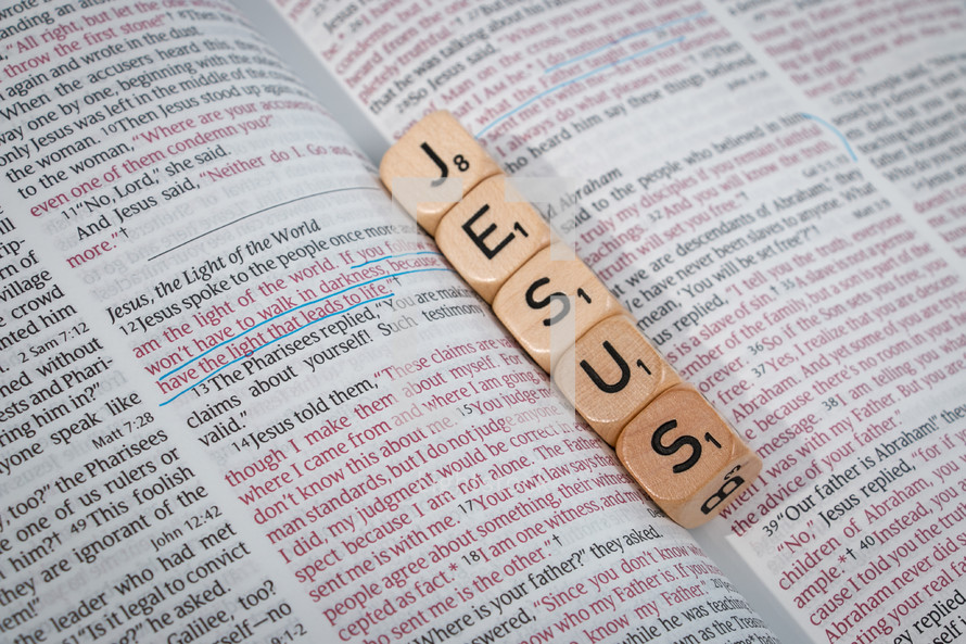 word Jesus in scrabble pieces on the pages of a Bible 