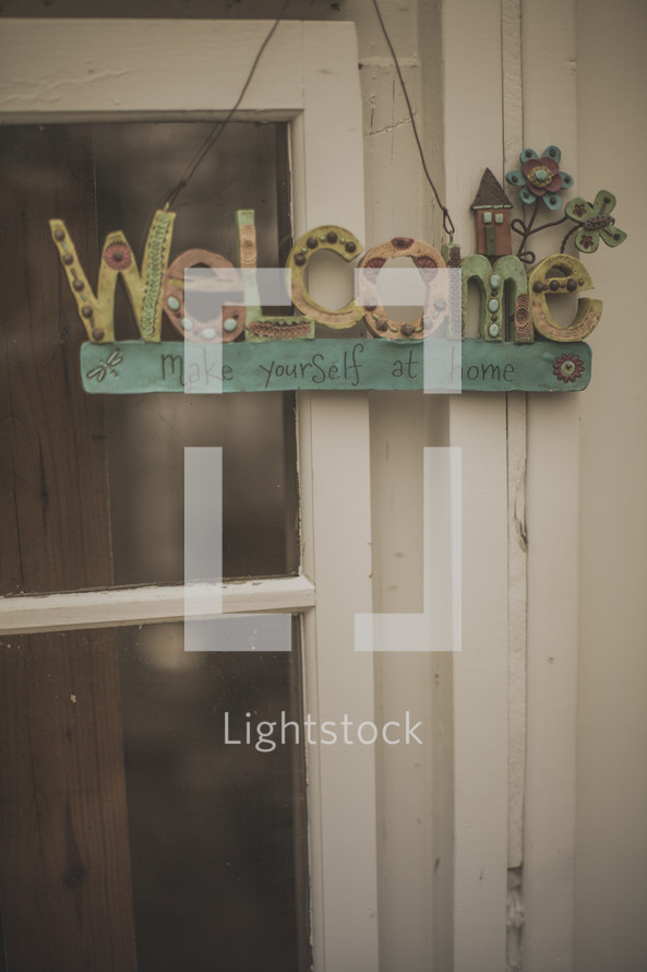 A welcome sign hanging from a window