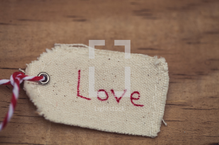 A Christmas gift tag reading "Love," on a wood grain background.