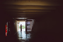 a woman standing at the end of a dark hallway 