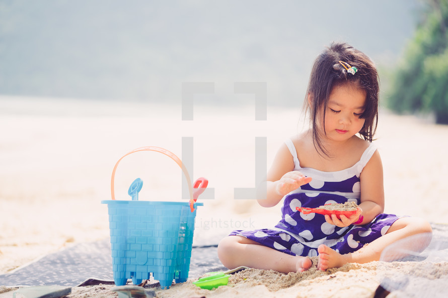 a little girl playing in the sand on a beach 