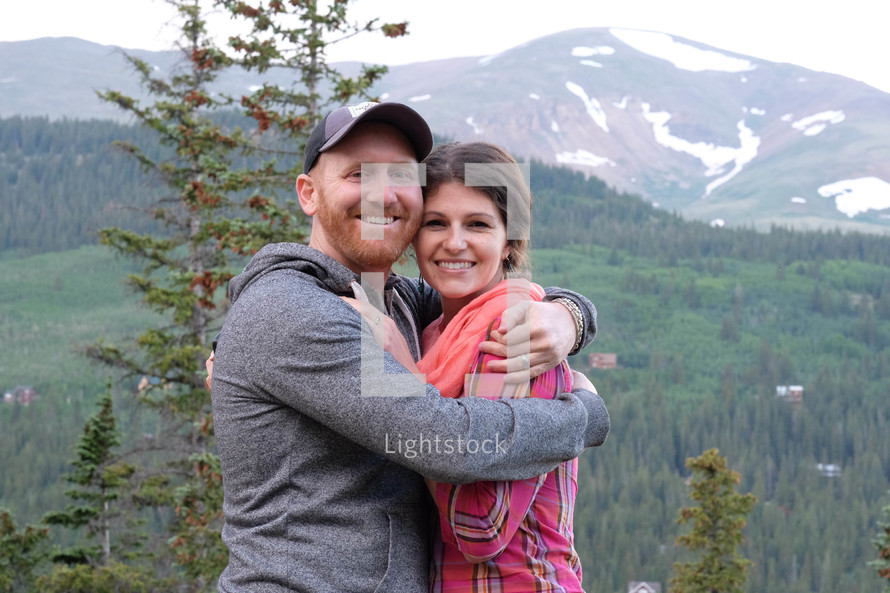 couple hugging in front of a mountain view 