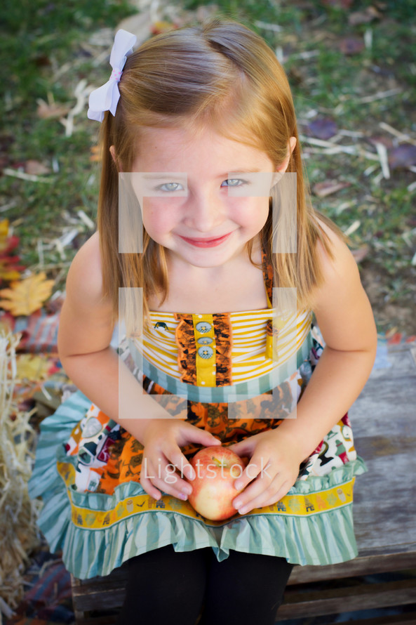 smiling toddler girl holding an apple 