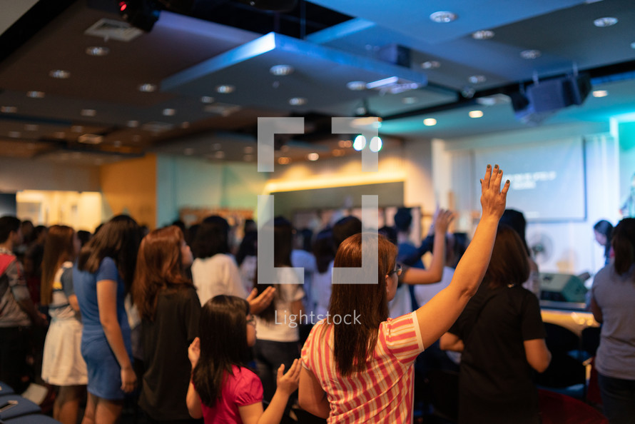 women and children with hands raised during a worship service 