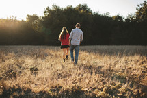 couple walking holding hands in a field