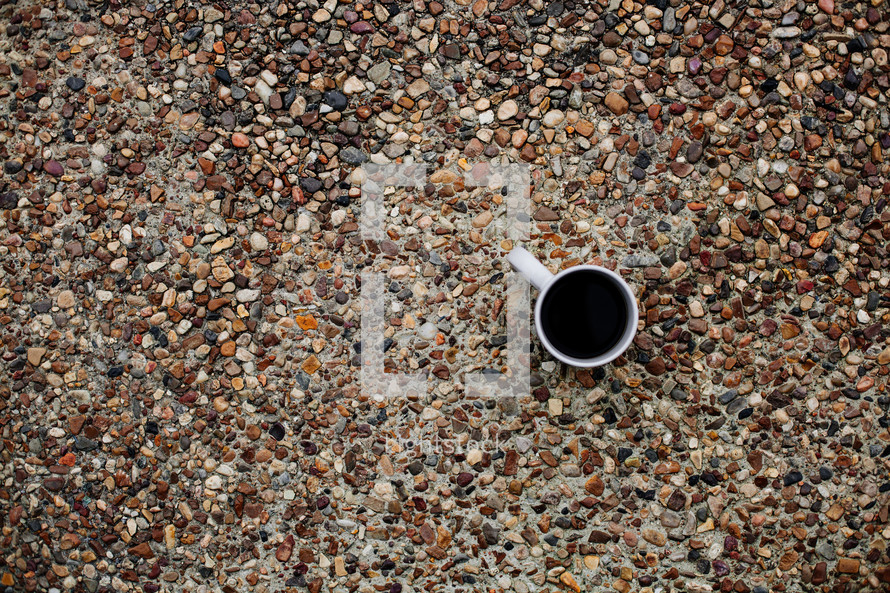 coffee mug on gravel sidewalk 