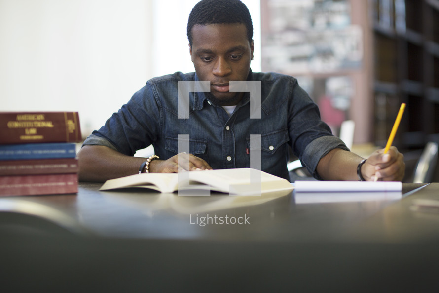 a male student studying in a library. 