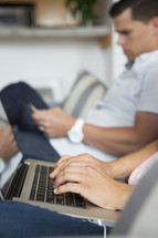 a woman sitting on a couch next to a man while typing on a laptop computer 