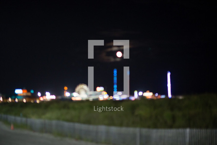 The moon over a seaside amusement park at night 