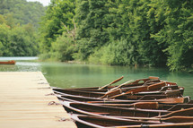 Row boats lined up at a dock on a river.