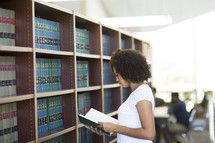 a woman looking at books in a library 