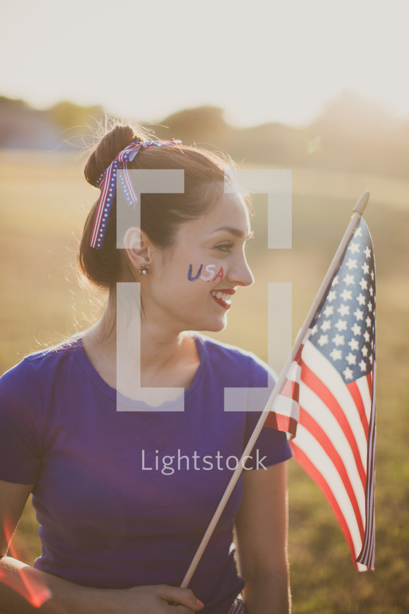 A young woman with USA face paint holding an American flag
