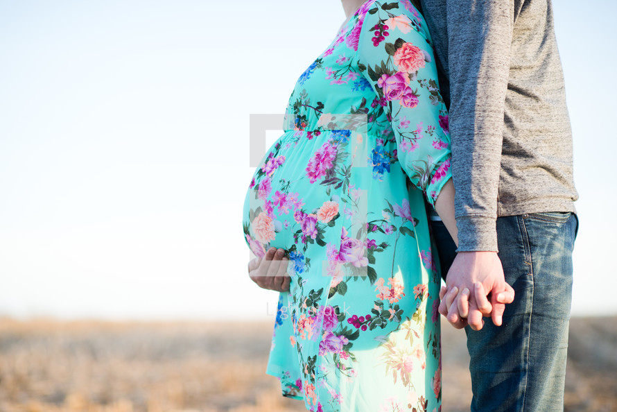 expecting couple on a farm standing back to back 