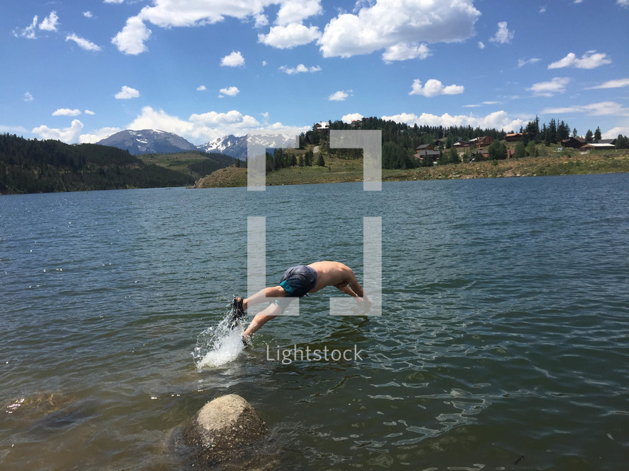 man diving in to a lake 