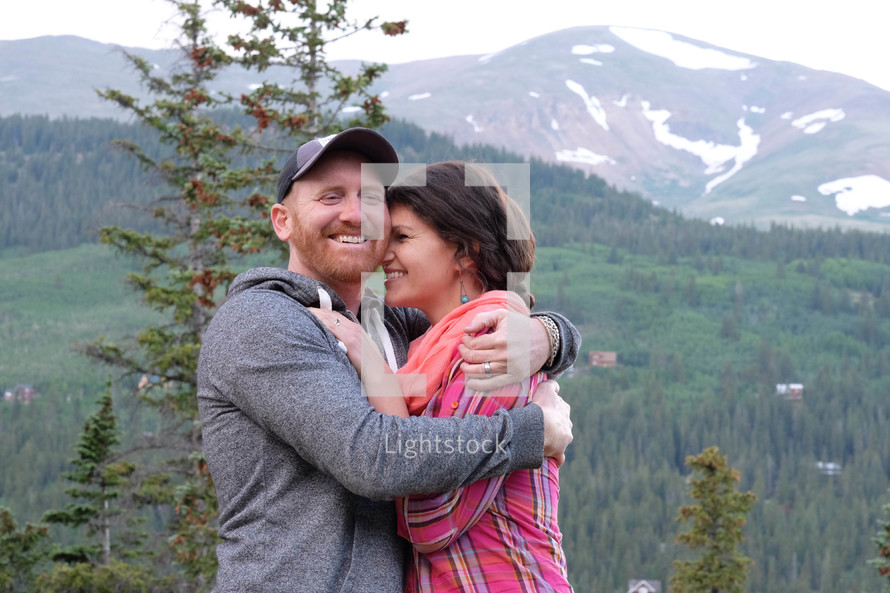 couple hugging in front of a mountain view 