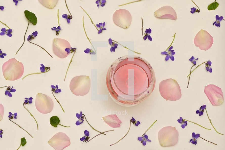 Rose Wine In Glass With Spring Flowers and Petals Background