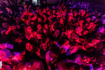 A crowd of young people under a red light.