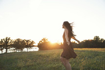a woman dancing by herself in a field.