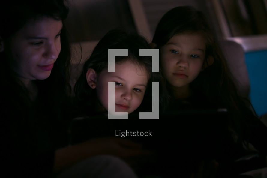 Young Mother watching a show with her children at home on in the dark