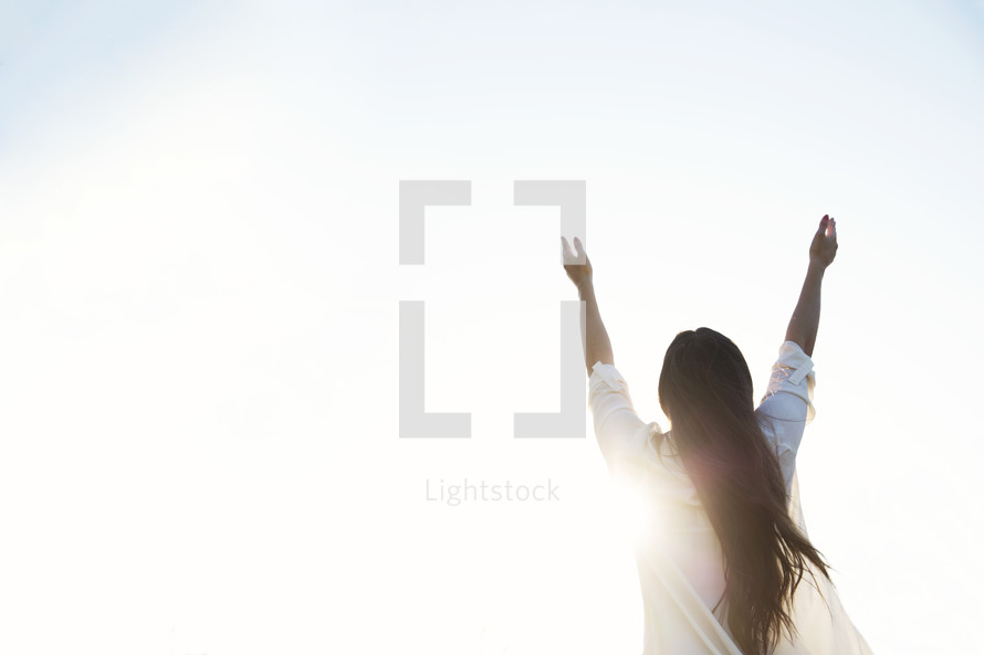 woman standing outdoors with raised hands 