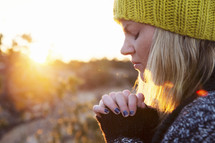 a woman in prayer outdoors in the winter.