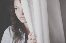 woman peeking from behind a curtain 